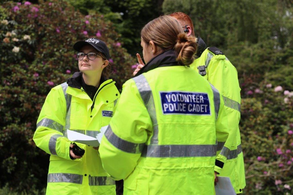 Three cadets stand in group discussing the incident, just as they are about to use a radio.