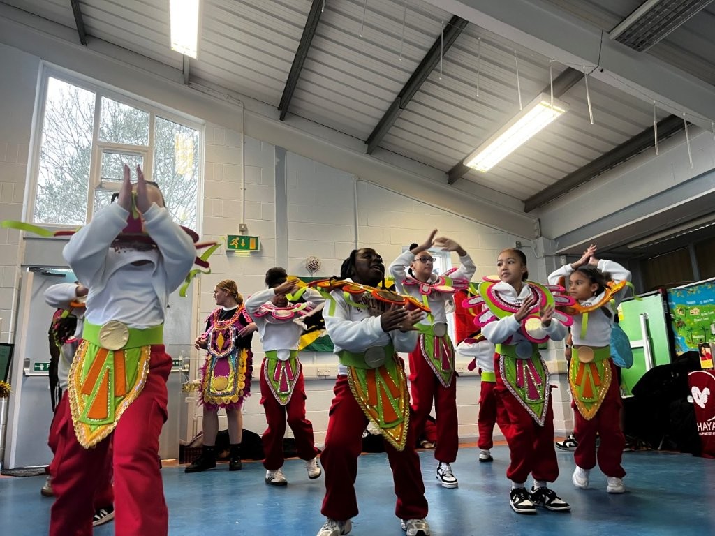 A group of dancers wearing colourful carnival costumes perform at a talent show.