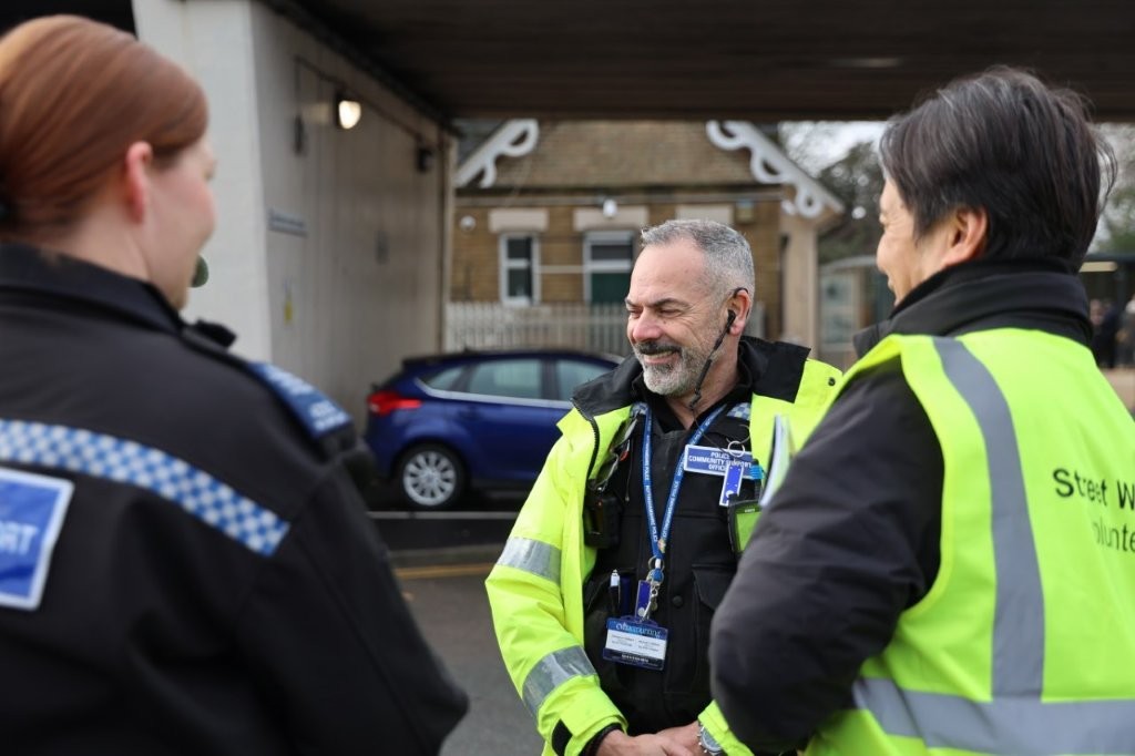 Two PCSOs stop and chat with a volunteer from Street Watch, who is wearing a branded high-vis vest.