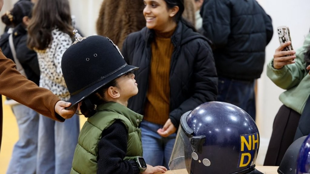 A child poses for a photo, trying on a police hat at a family fun afternoon.