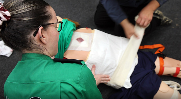 A St John Ambulance emergency responder giving a first aid demonstration on a dummy