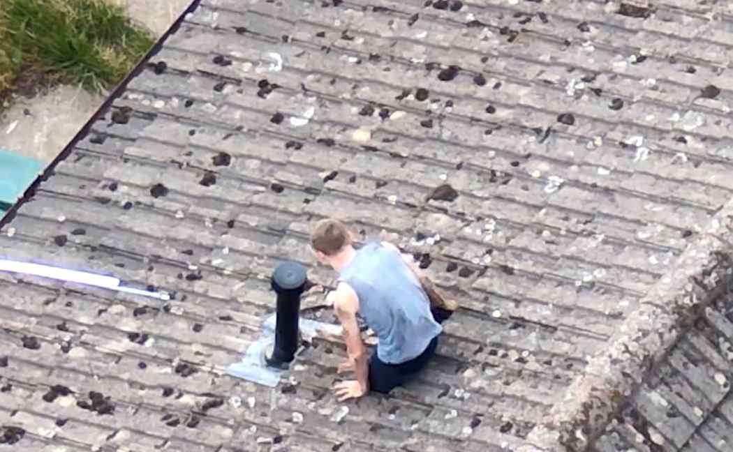 James Rylance climbing through a hole onto the roof
