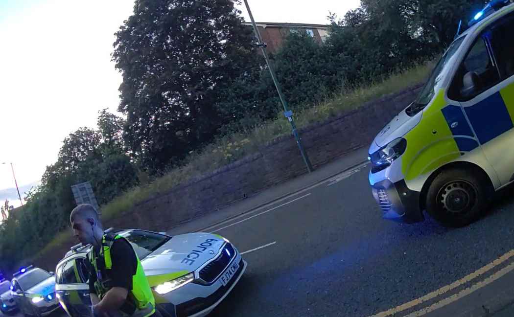 Officers stands in front of two police vans