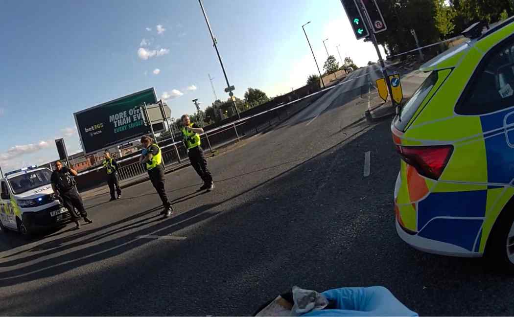 Drugs held by officer, with police car and other officers in background