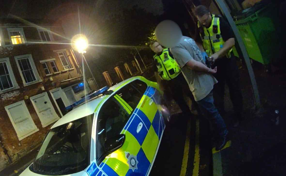 Two officers put suspect in police car