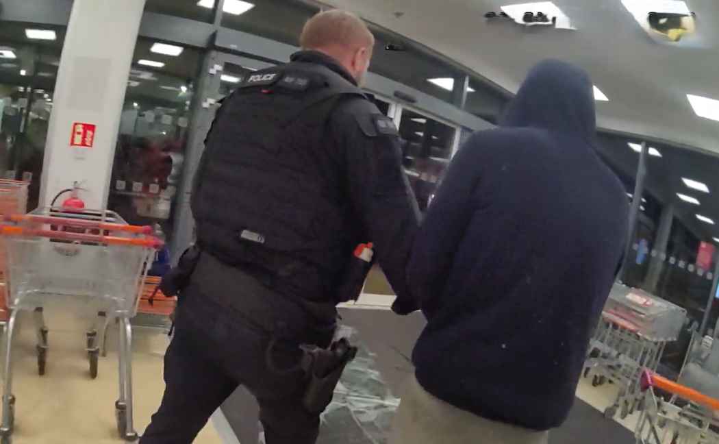 Officer leads suspect out of shop