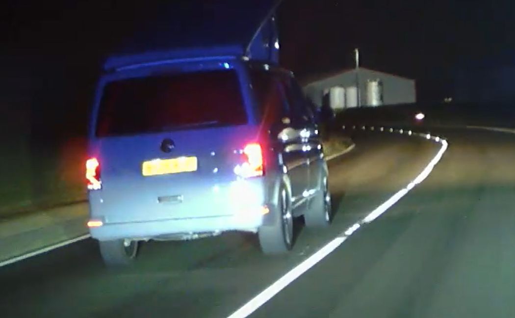 blue campervan driving at night with its pop up bed exposed
